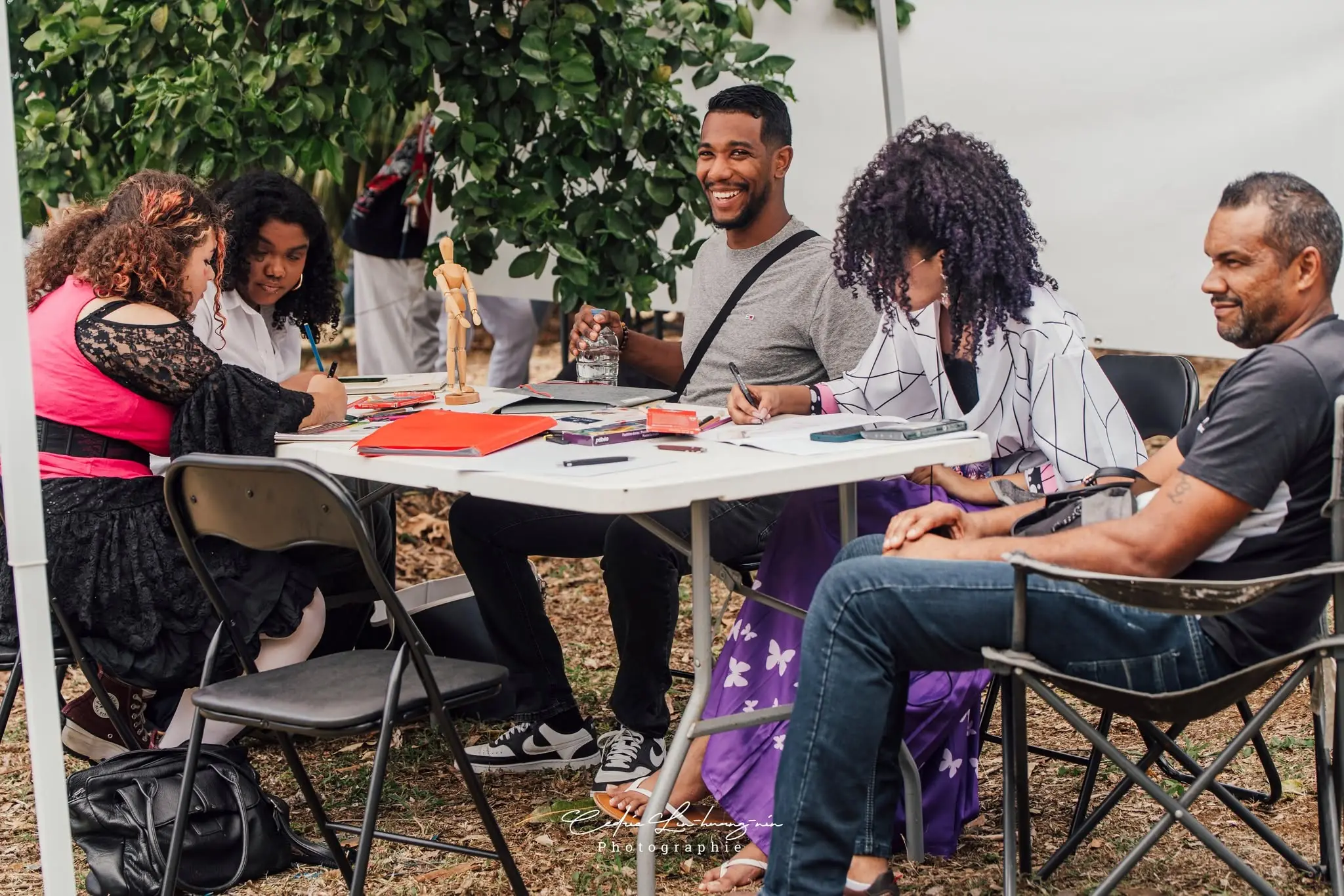 Des artistes et des participants dessinent ensemble autour d’une table pendant Kiltir Geek 3