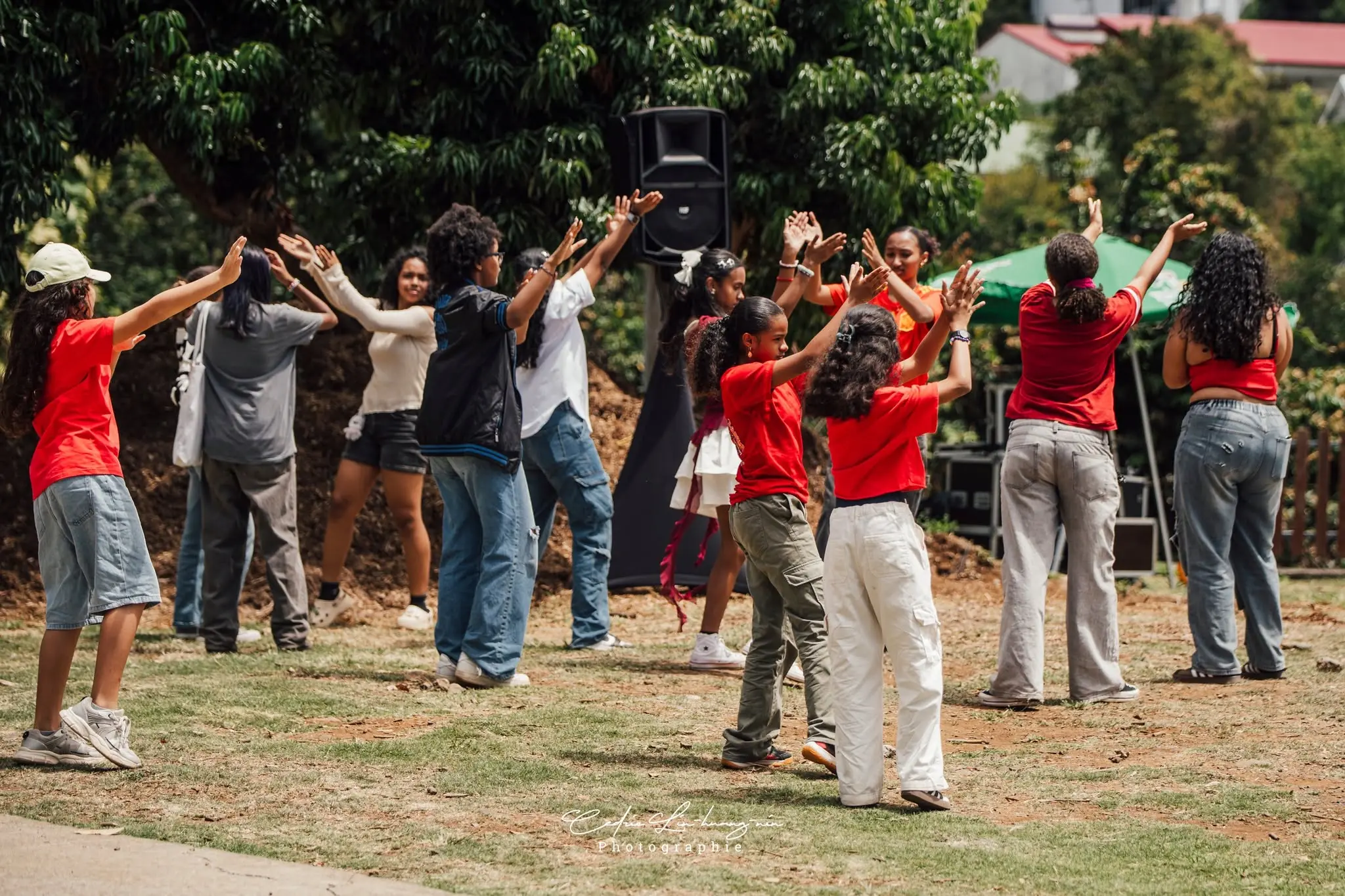 Un groupe de danseurs en rouge et blanc réalise une chorégraphie K-pop en plein air